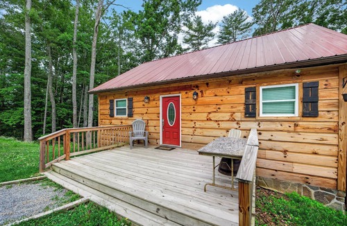 Galax House | A secluded, multi-level log cabin featuring a spacious wooden deck, open-concept living, a fully equipped modern kitchen, and comfortable sports-themed bunk rooms.
